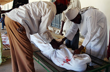 Somalians prepare the body of a man killed in clashes on the streets of Mogadishu during heavy fighting between insurgents and Ethiopian troops on April 21, 2008.